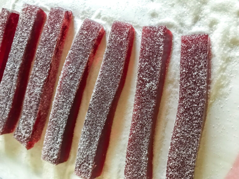 Strips of cranberry gummy candy on sugared surface