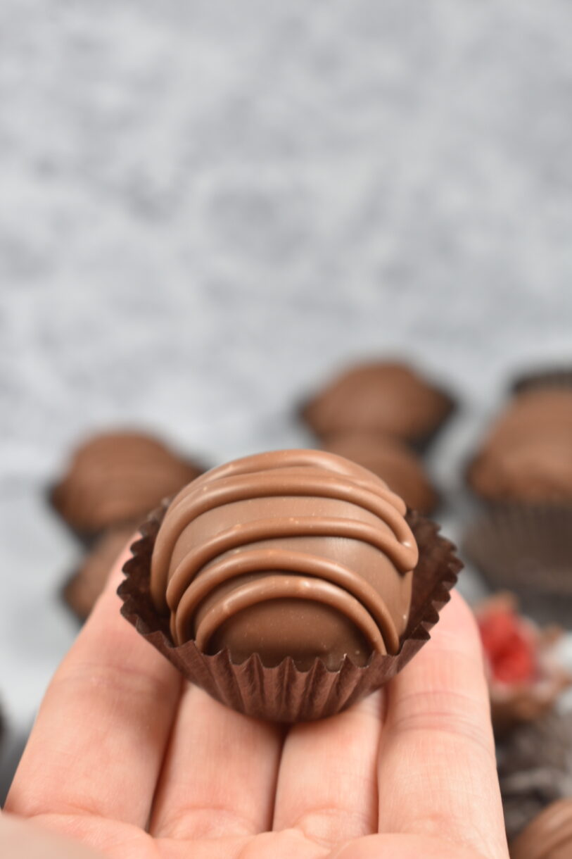 Hand holding a homemade chocolate in a truffle cup