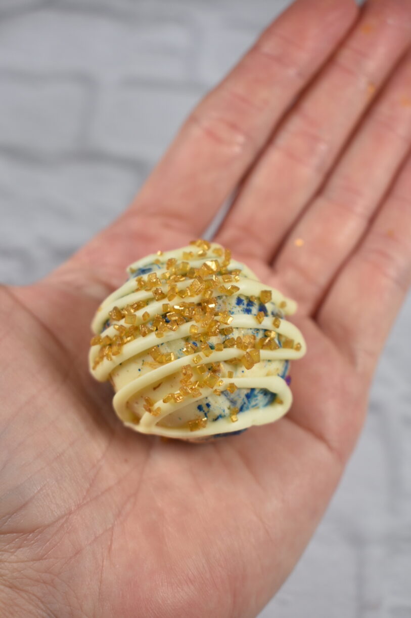 Hand holding a white chocolate and salted caramel chocolate bomb