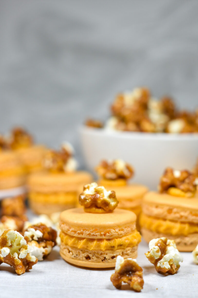 Caramel popcorn macarons and a bowl of caramel corn on a white background