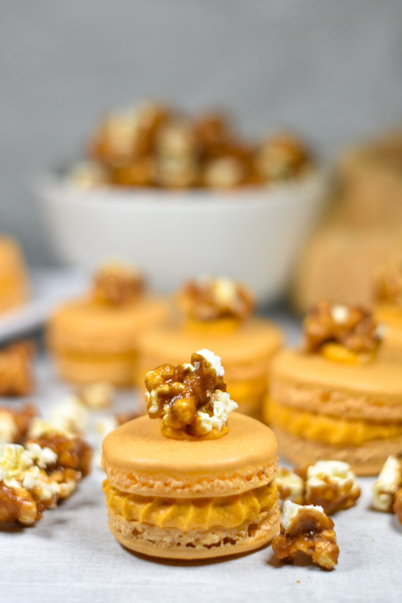 A macaron filled with caramel buttercream and a kernel of popcorn on top