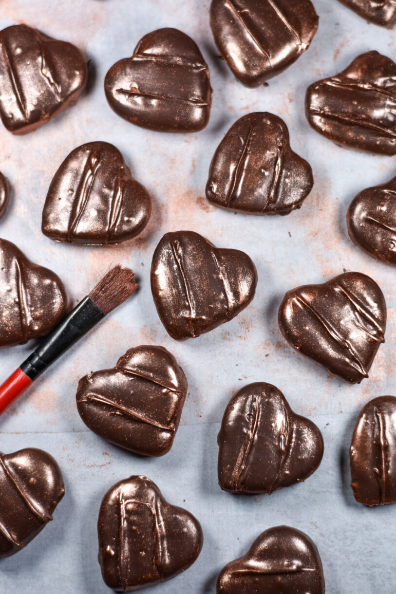 Heart shaped chocolate peppermint patties and a paintbrush, on a white surface