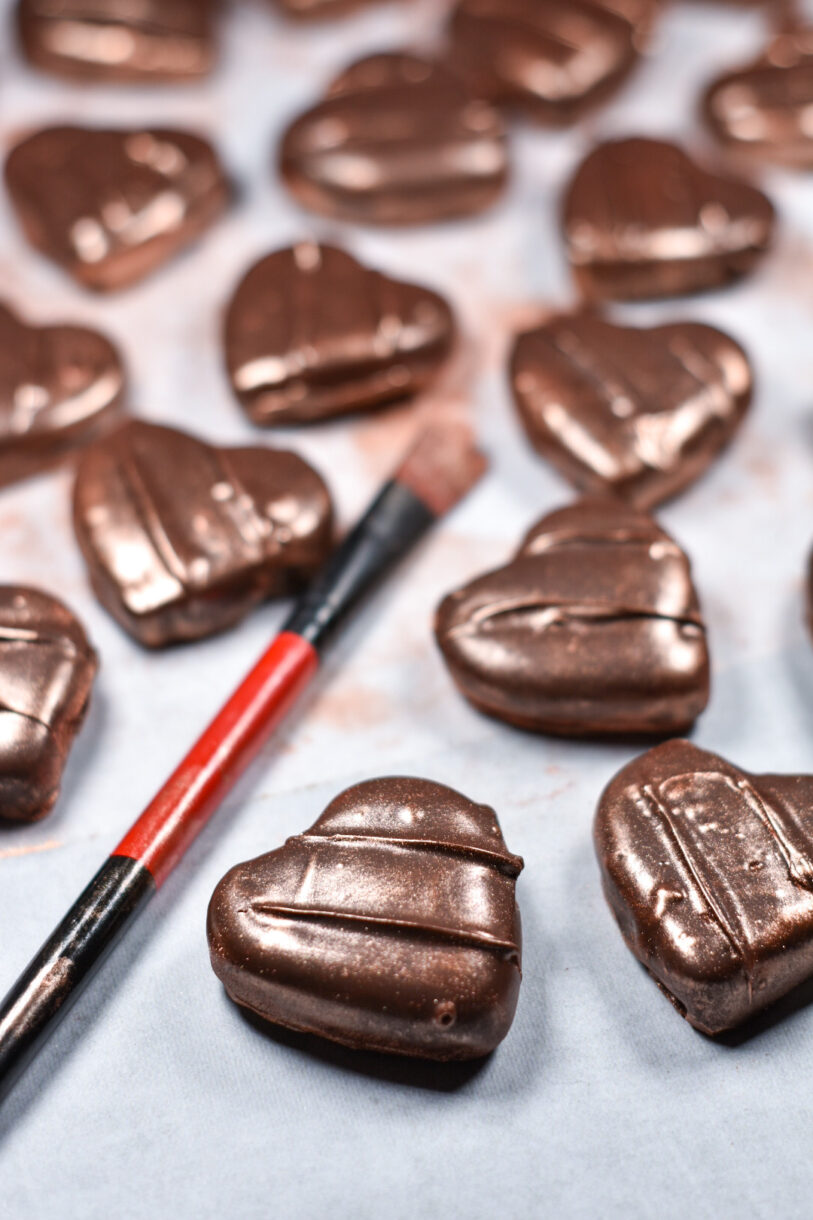 Homemade chocolate peppermint patties and a paintbrush, on a white surface