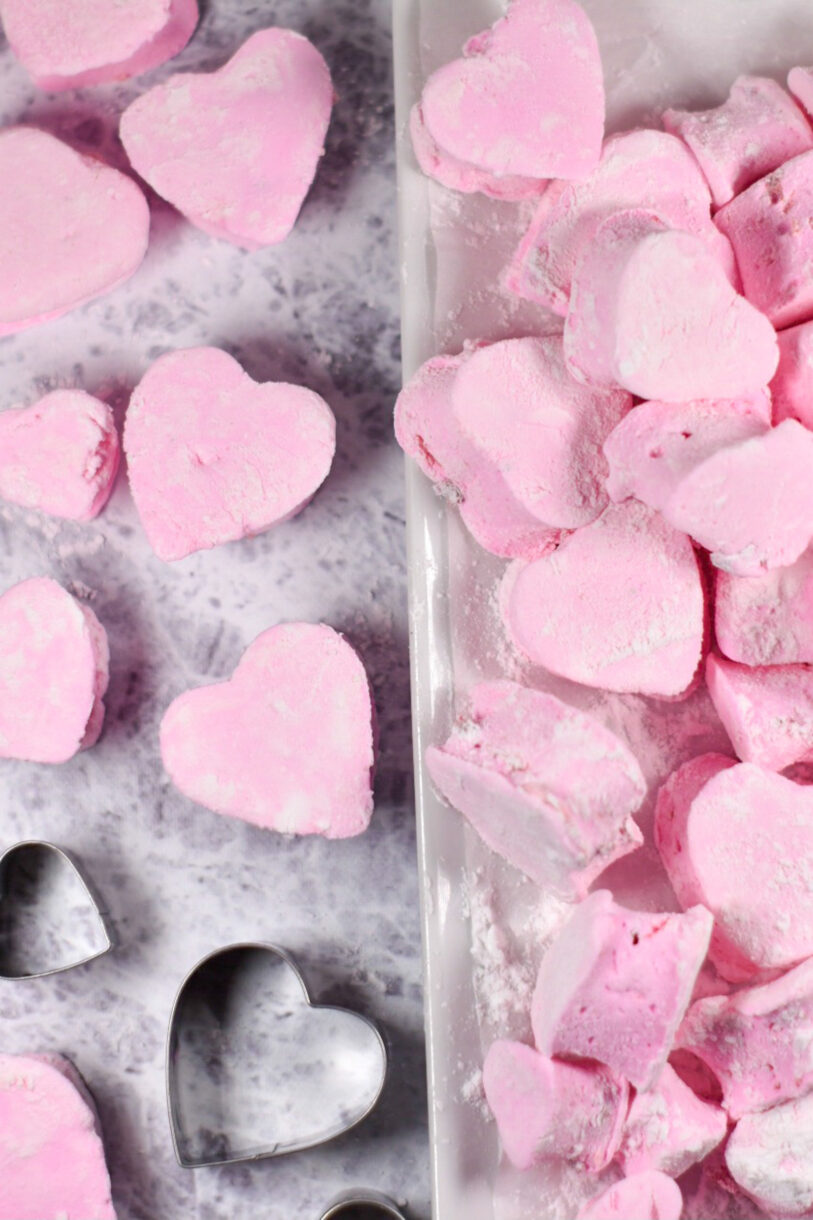 Homemade strawberry marshmallows shaped like hearts, arranged on a white rectangular tray