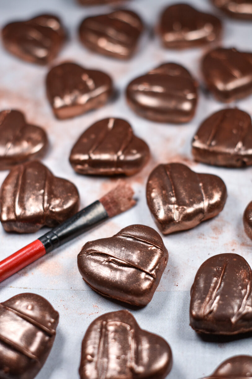 Homemade chocolate peppermint patties and a paintbrush, on a white surface