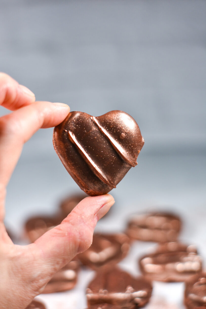 Hand holding a single heart-shaped chocolate