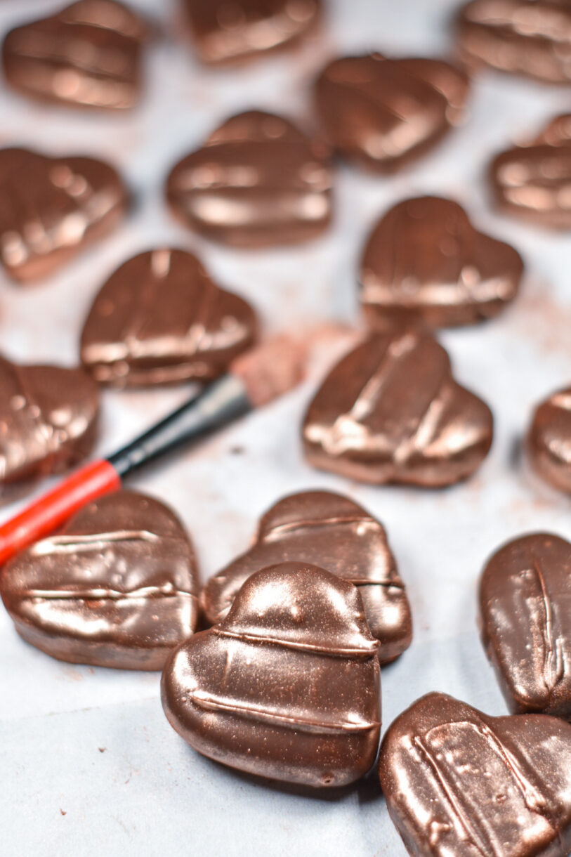 Heart shaped chocolate peppermint patties and a paintbrush, on a white surface