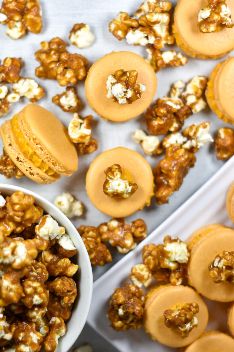 Caramel popcorn macarons and a bowl of popcorn on a white surface
