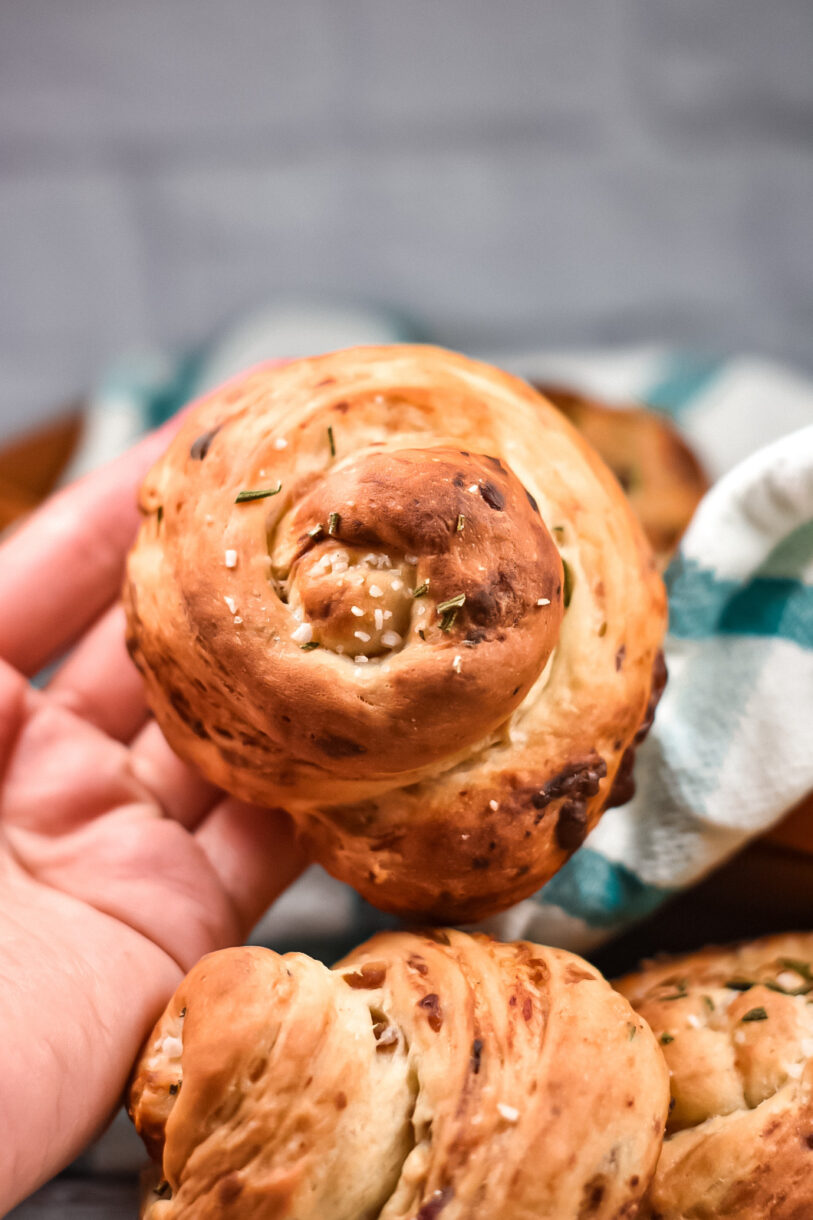 Hand holding a dinner roll with bleu cheese, rosemary and dates