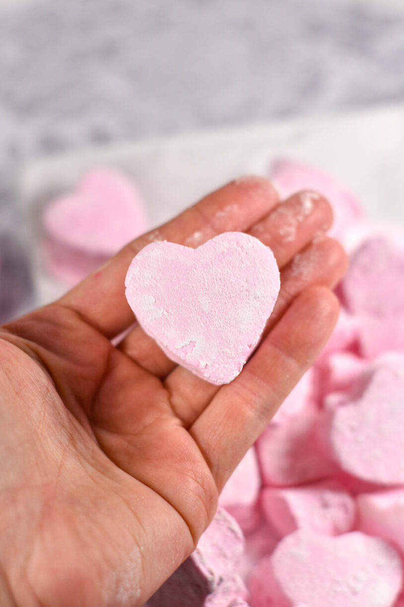 Hand holding a powdery pink heart marshmallow