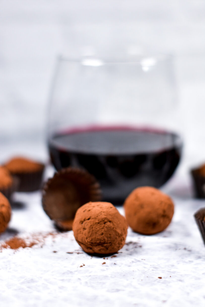 Glass of red wine with homemade chocolate truffles, on a white background
