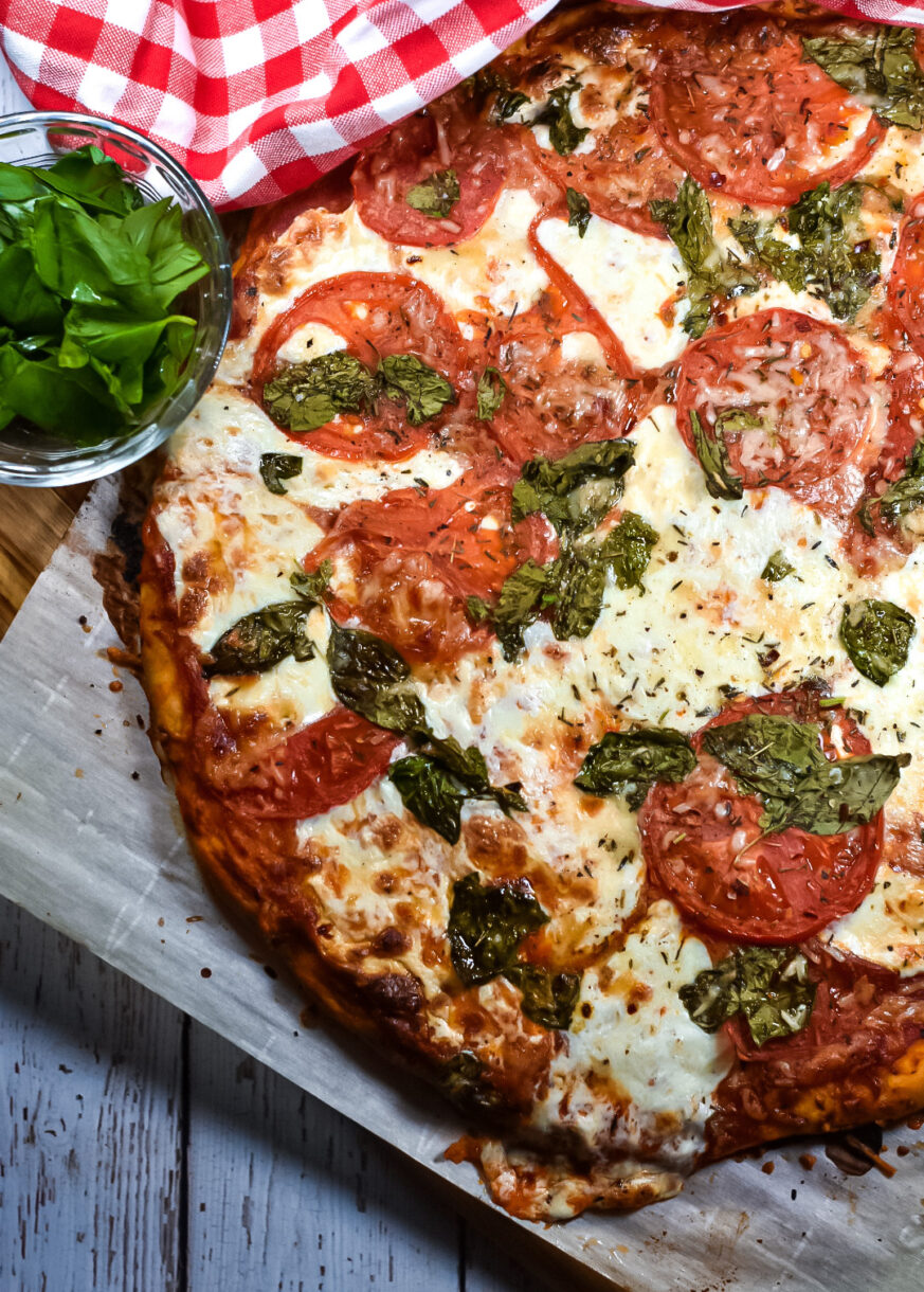 A pizza with cheese, tomatoes, and basil
