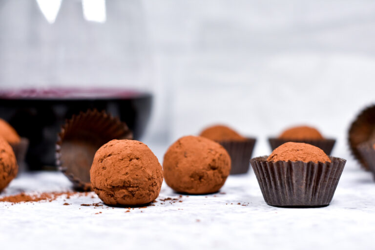 Horizontal shot of truffles and a glass of red wine on a white background