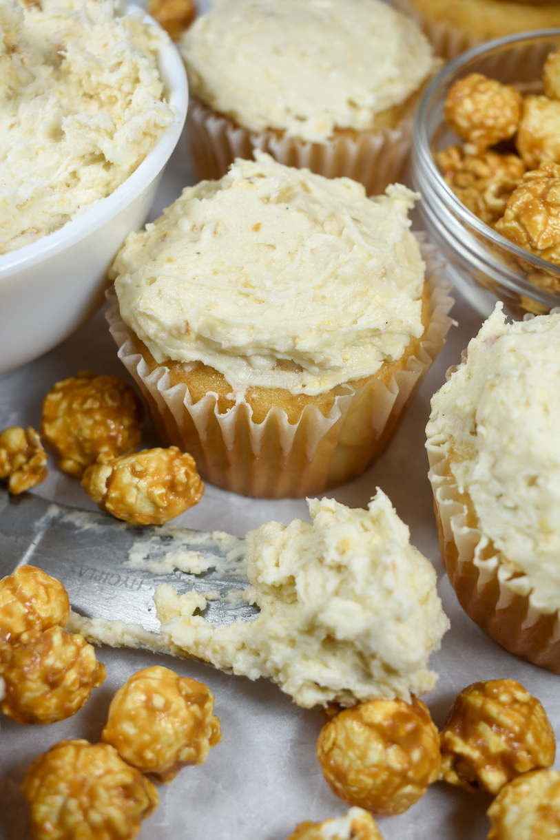 cupcakes frosted with caramel buttercream surrounded by pieces of caramel corn