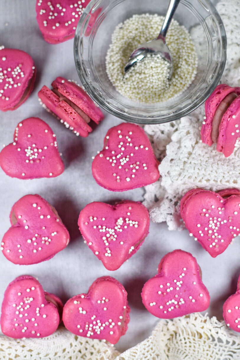 Heart macarons, lace fabric, and a bowl of nonpareils