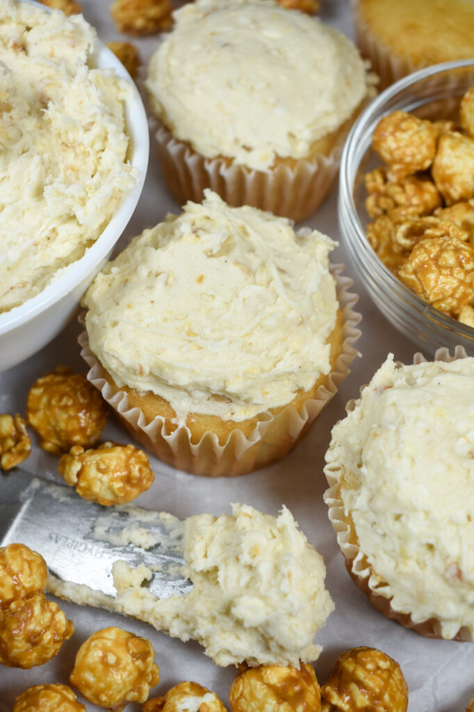 cupcakes frosted with caramel corn buttercream surrounded by pieces of caramel popcorn
