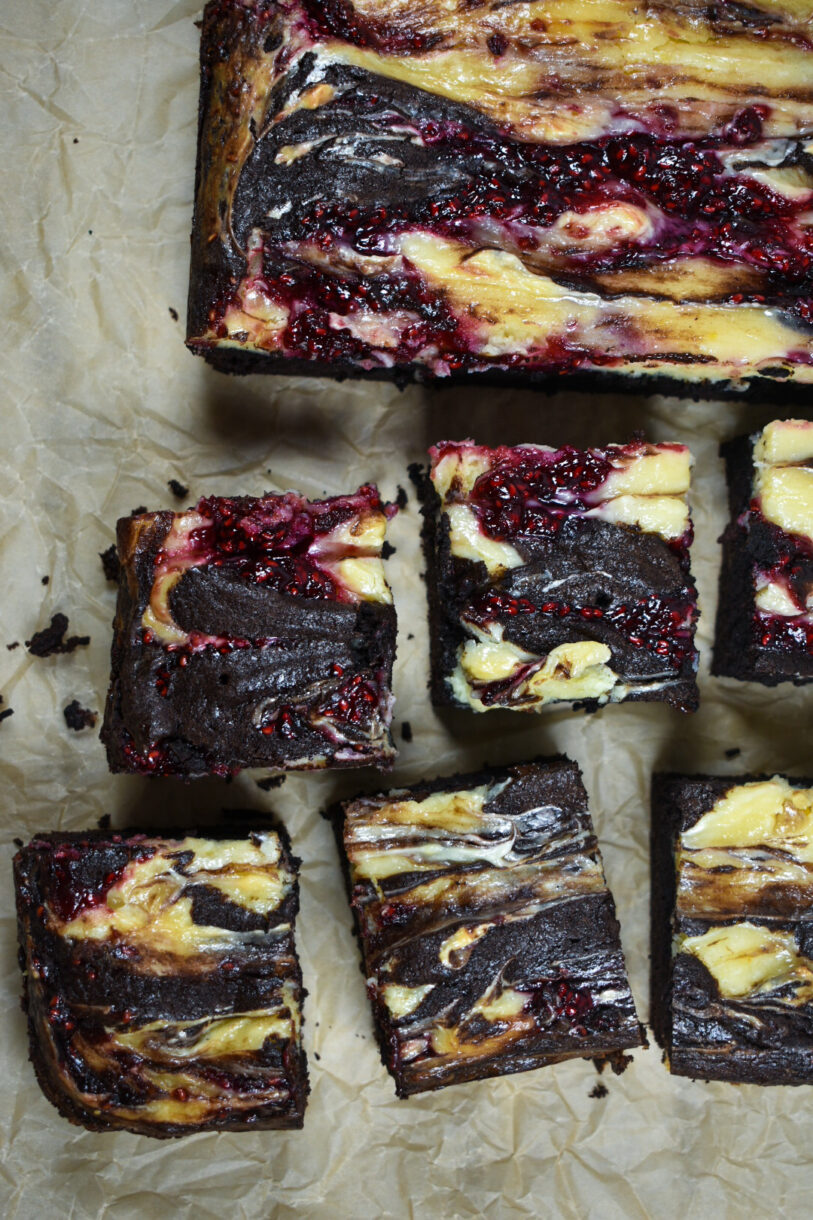 Raspberry cheesecake brownies on a sheet of crinkled baking parchment