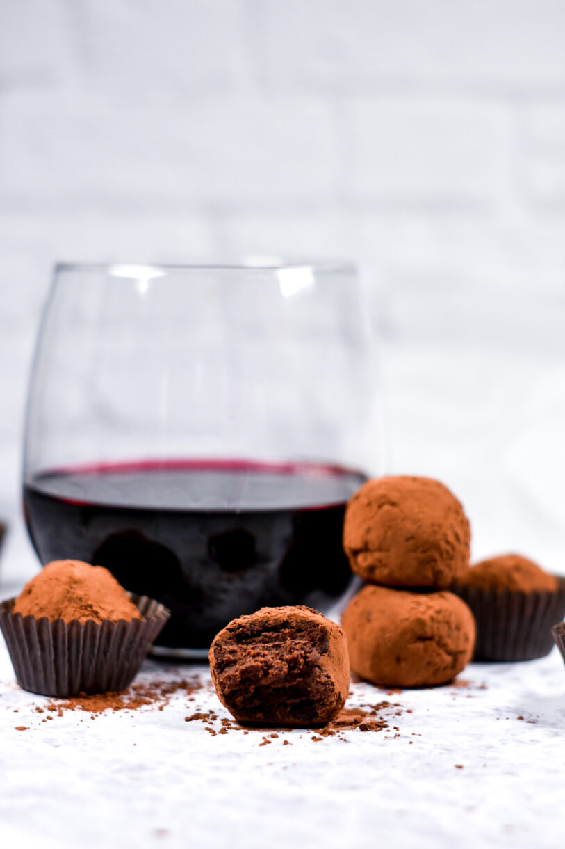 Chocolate truffles and a glass of red wine on a white background