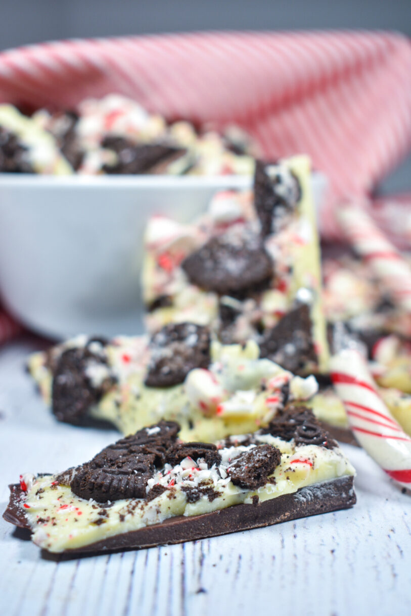Peppermint bark on a white wooden surface with a bowl and tea towel in the background