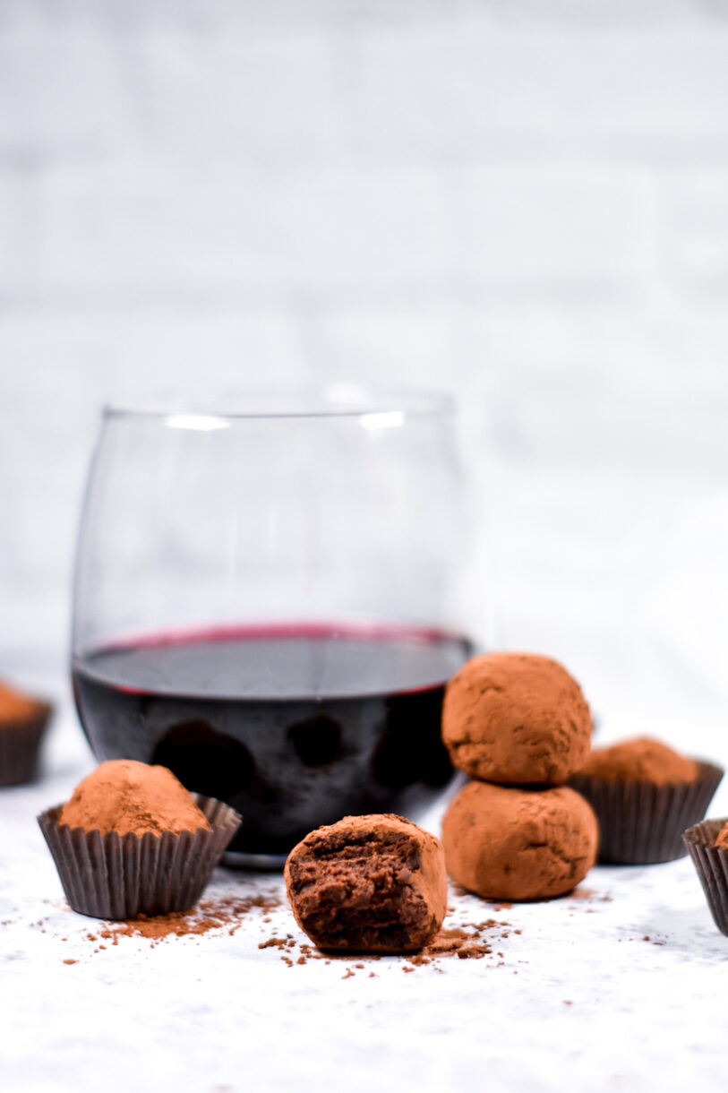 Chocolate truffles and a glass of red wine on a white background