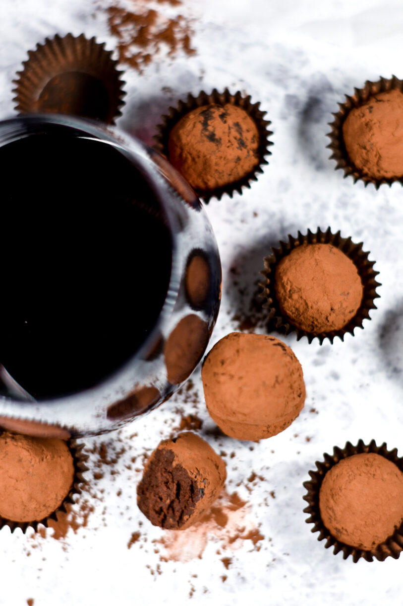 Looking down at homemade chocolate truffles and a glass of red wine