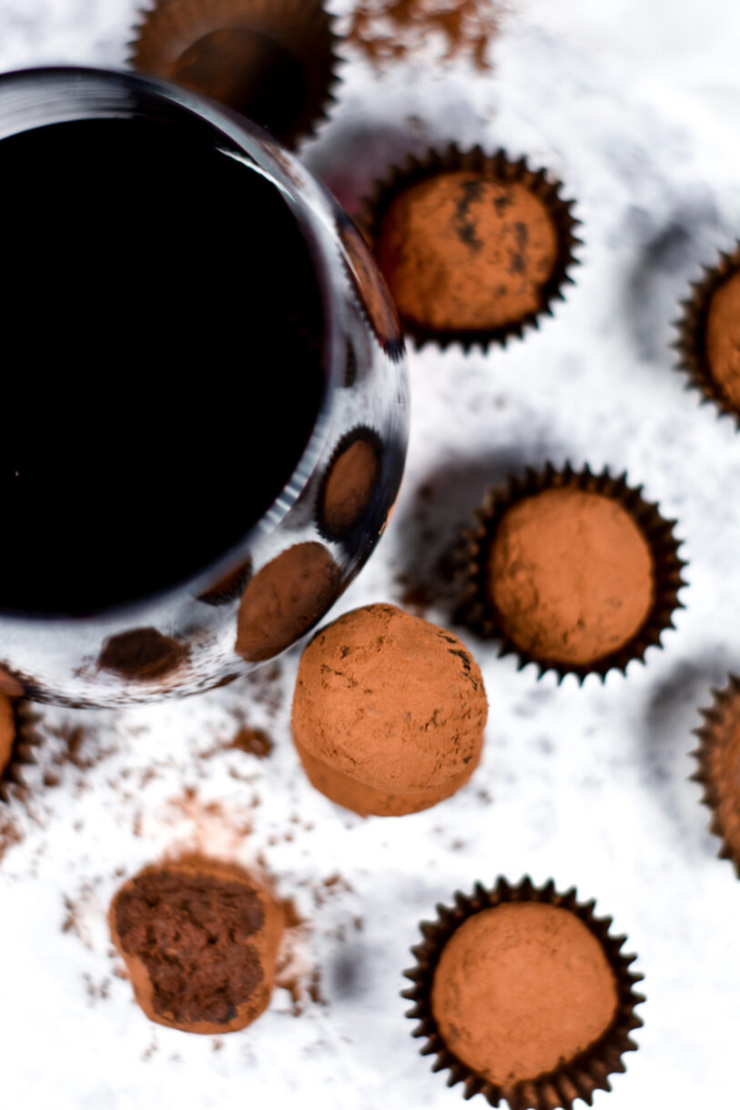 Glass of red wine with chocolate truffles, on a white background