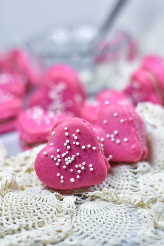 Ruby Raspberry Ganache frosting sandwiched between heart macarons