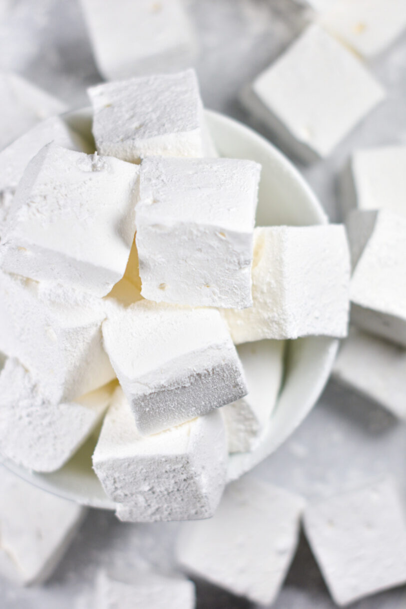 A bowl of homemade vanilla bean marshmallows on a white background