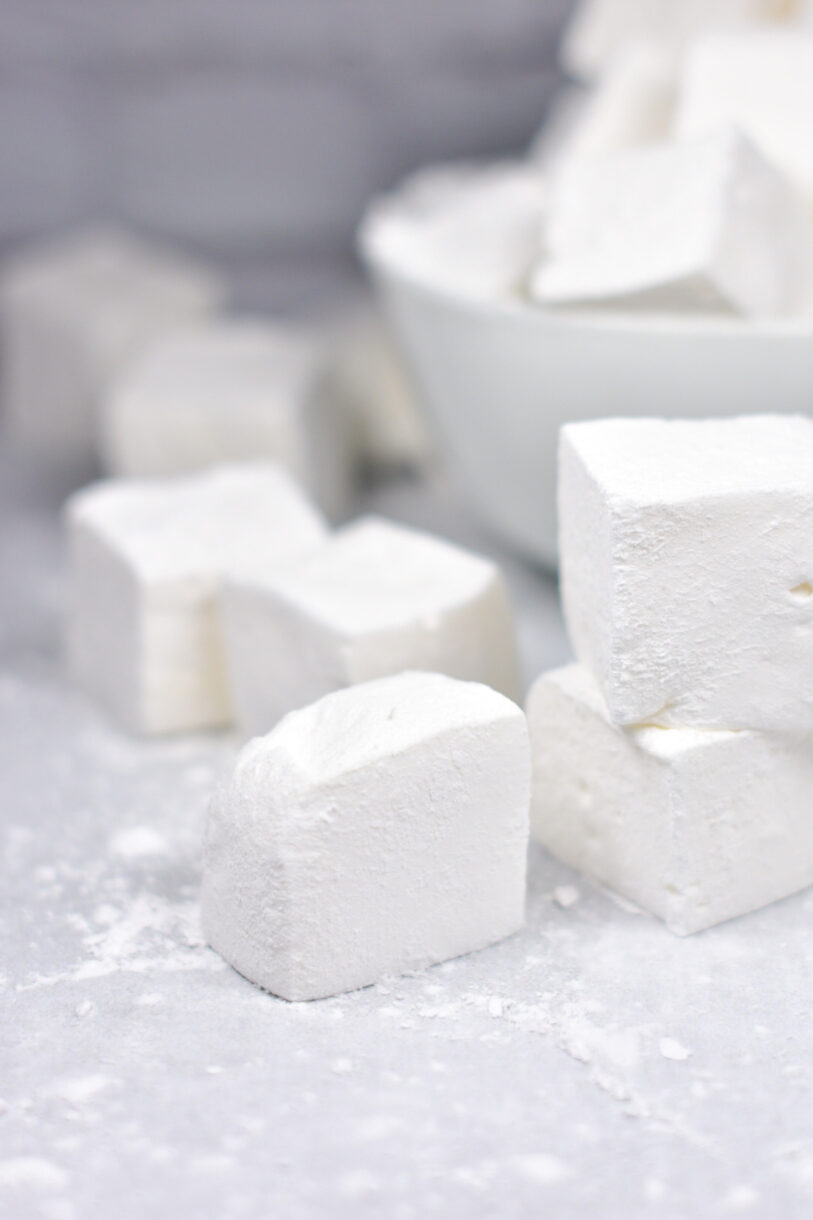 Vanilla bean marshmallows on a white surface, with white powder surrounding