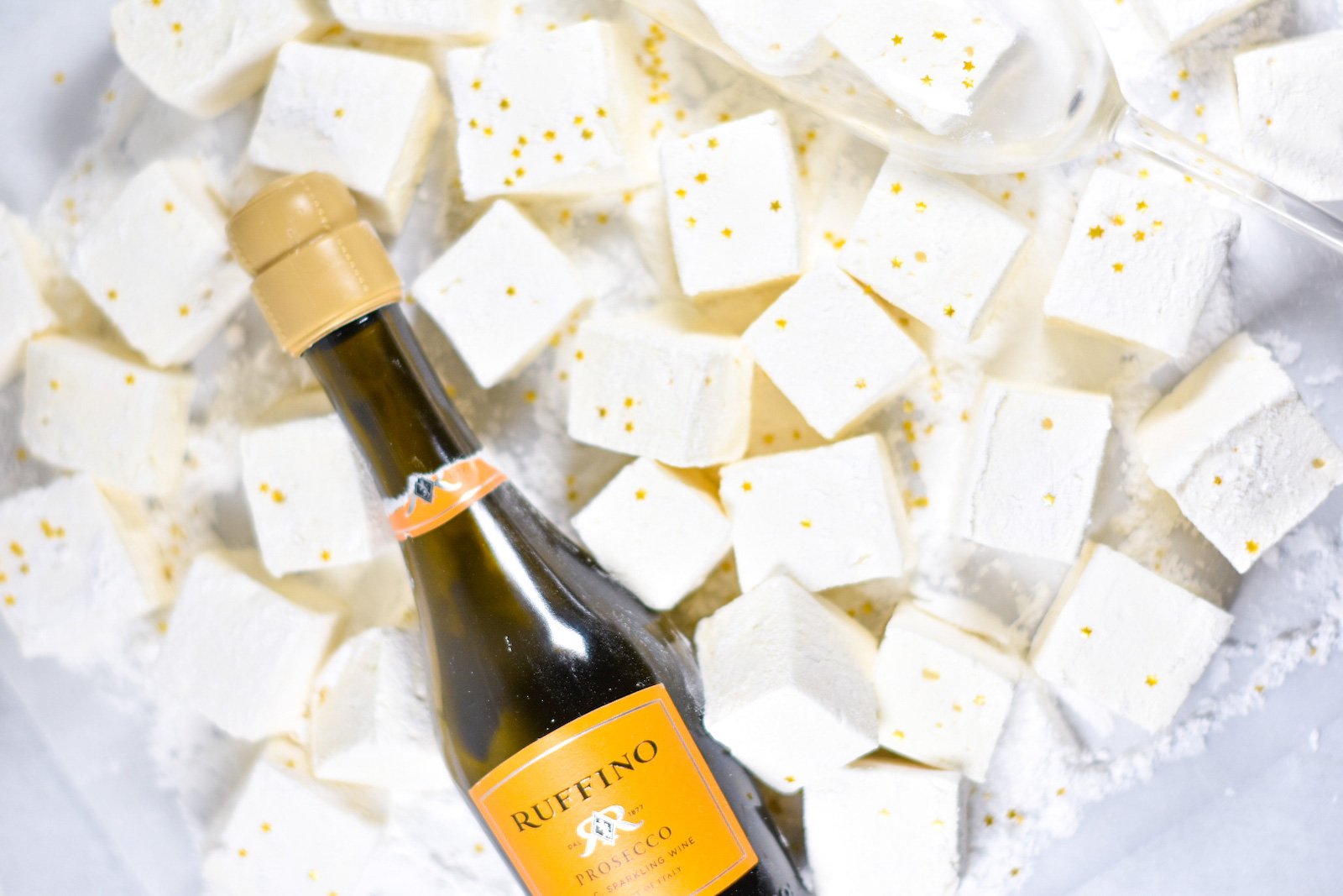 homemade marshmallows and a bottle of prosecco on a white surface