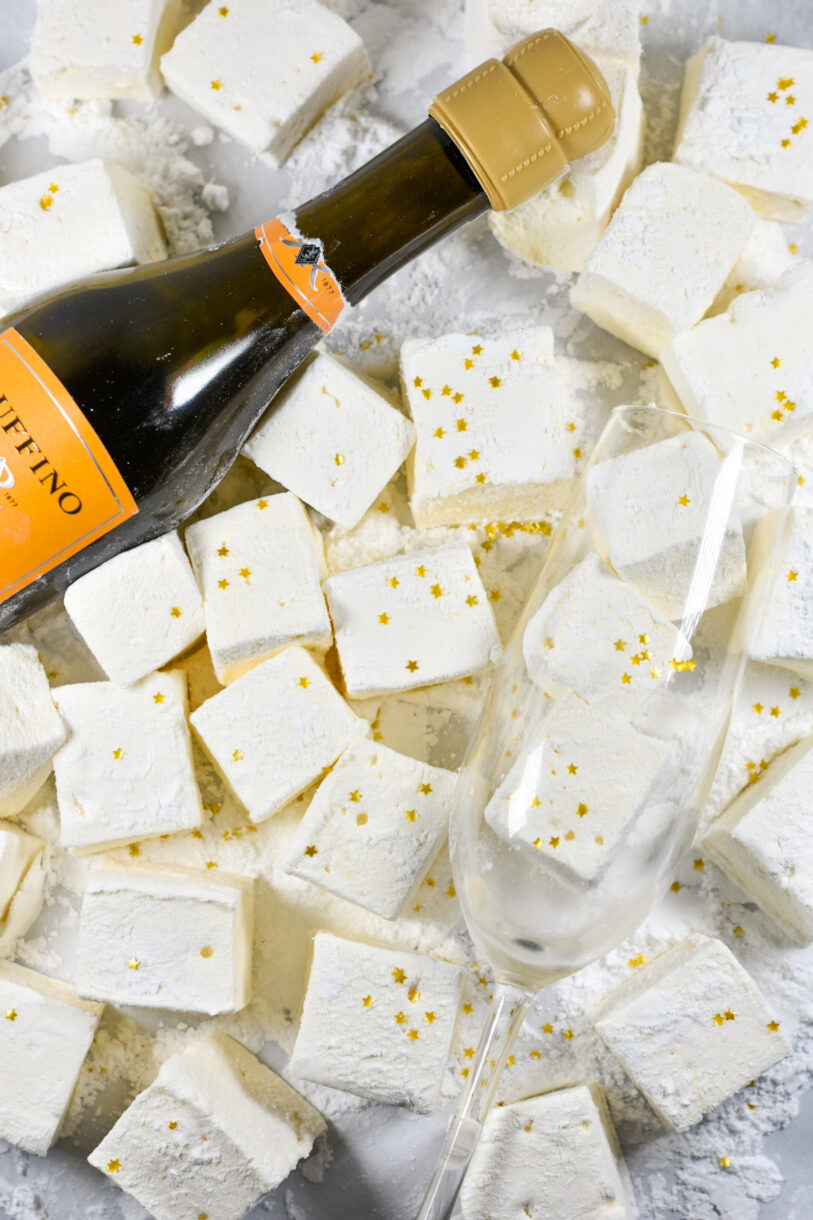 Prosecco marshmallows and a bottle of prosecco on a white surface