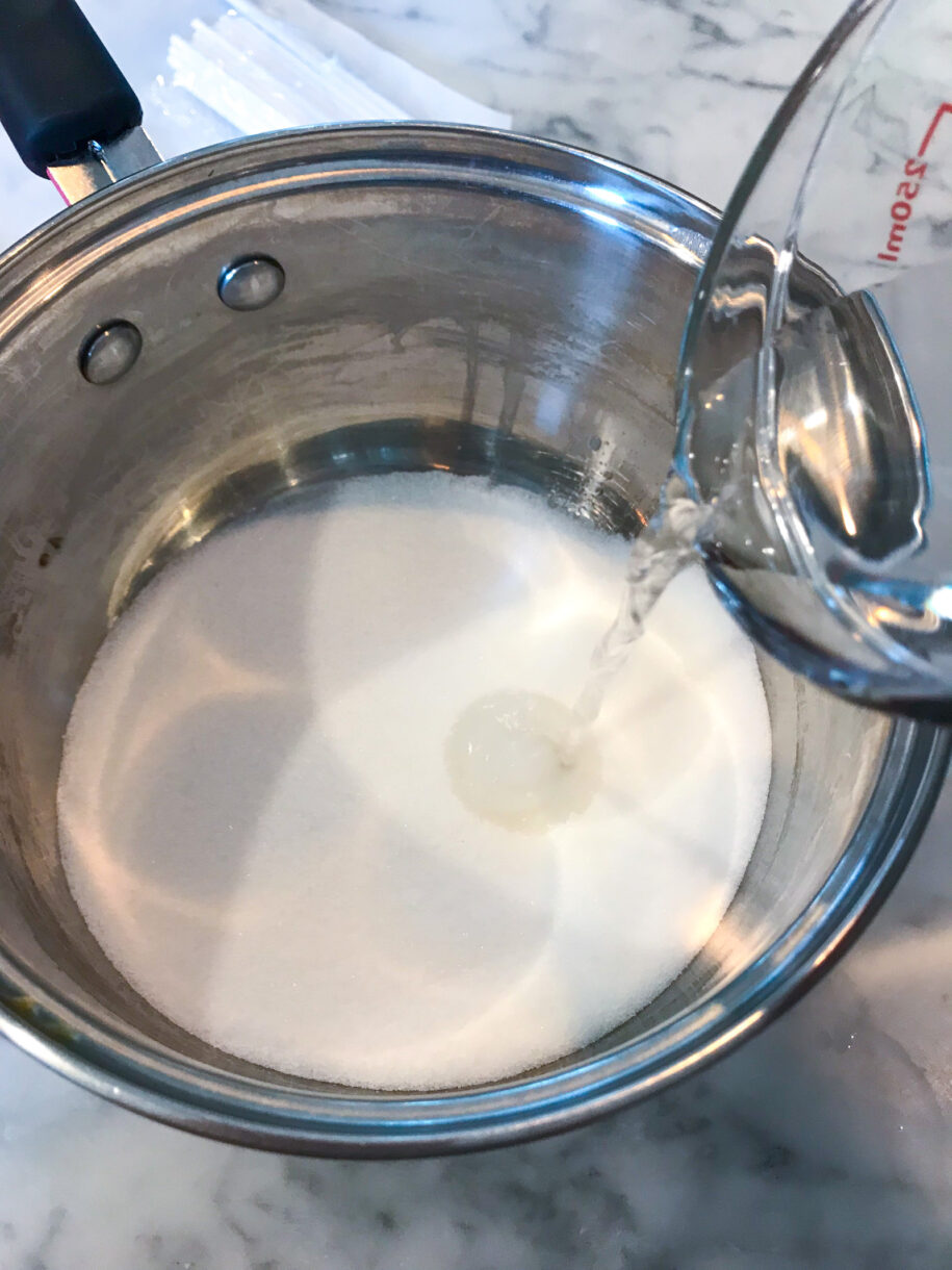 Measuring cup pouring water into a saucepan