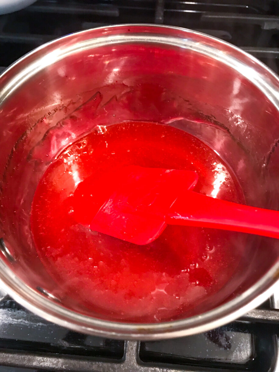 Lollipop sugar cooking in a saucepan with red spatula
