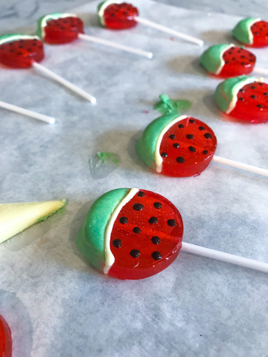 Decorating watermelon lollipops with white chocolate