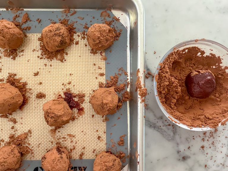 Rolling raspberry truffles in cocoa powder