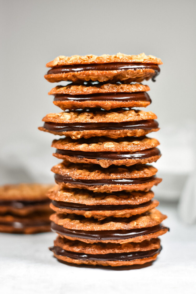 A stack of lace oatmeal sandwich cookies filled with chocolate ganache