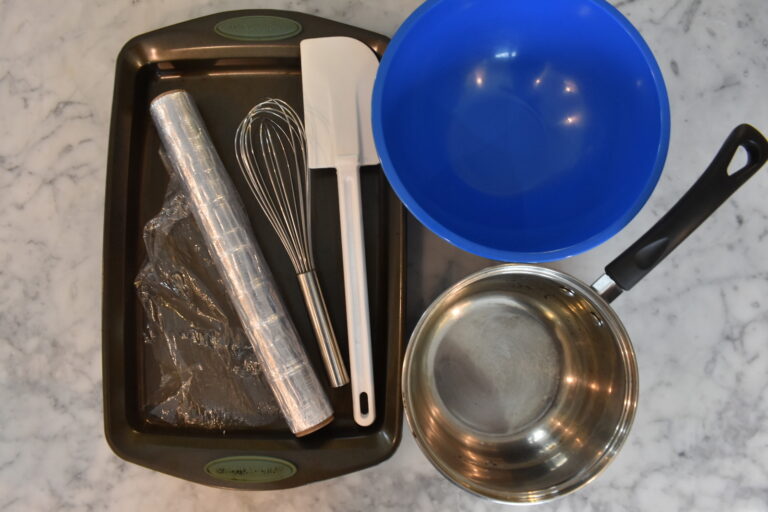 A tray, bowl, saucepan, and baking tools arranged on a marble countertop