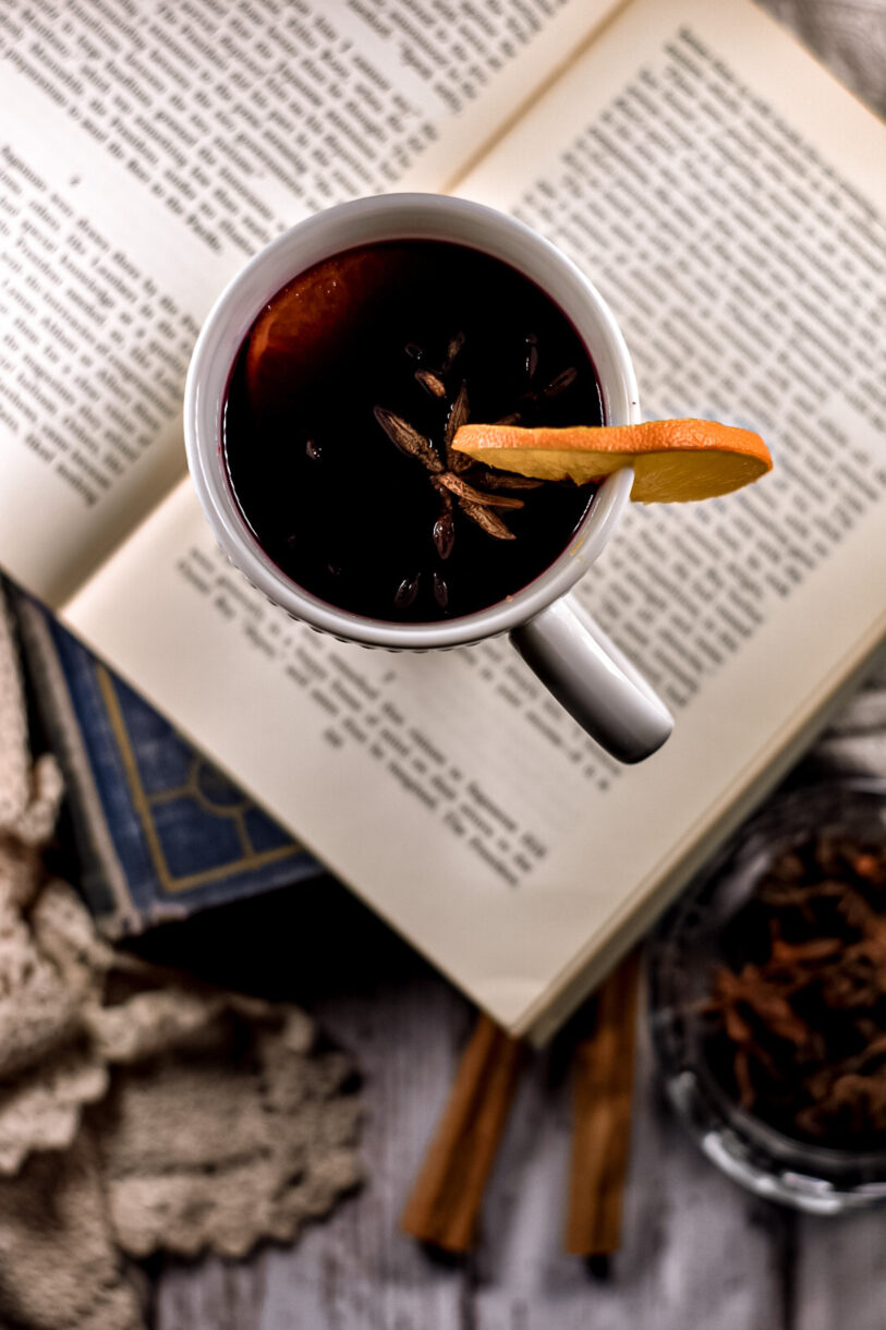 Mulled wine in a white mug, sitting on top of a stack of open books