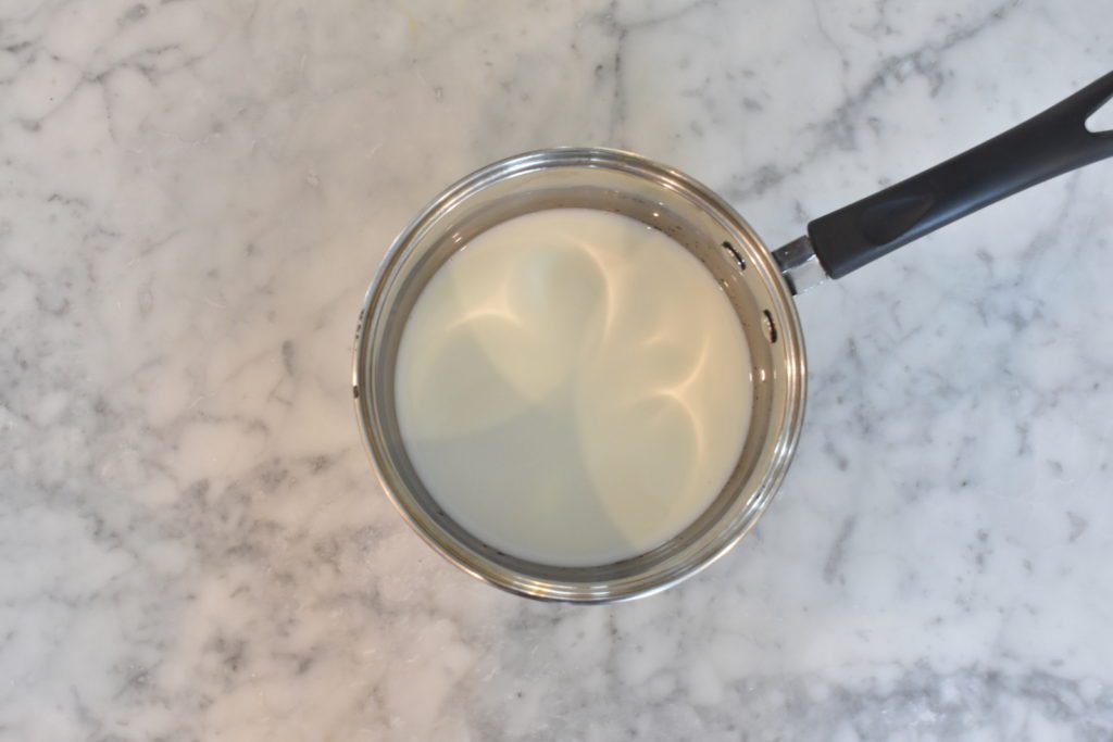 Milk and sugar in a suacepan on a marble countertop