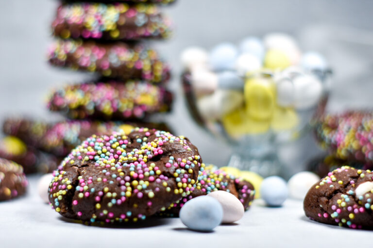 Chocolate mini egg cookies and a glass bowl of mini eggs on a white background