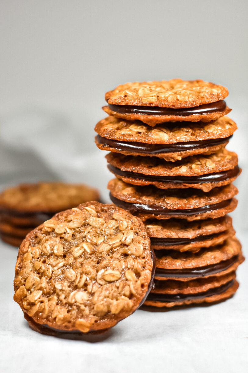 A stack of homemade oatmeal sandwich cookies with chocolate ganache