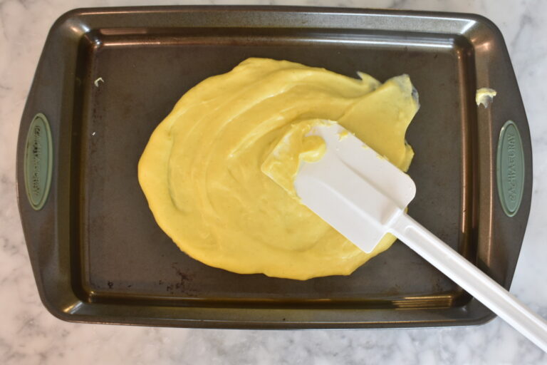 Spreading pastry cream on tray with a rubber spatula
