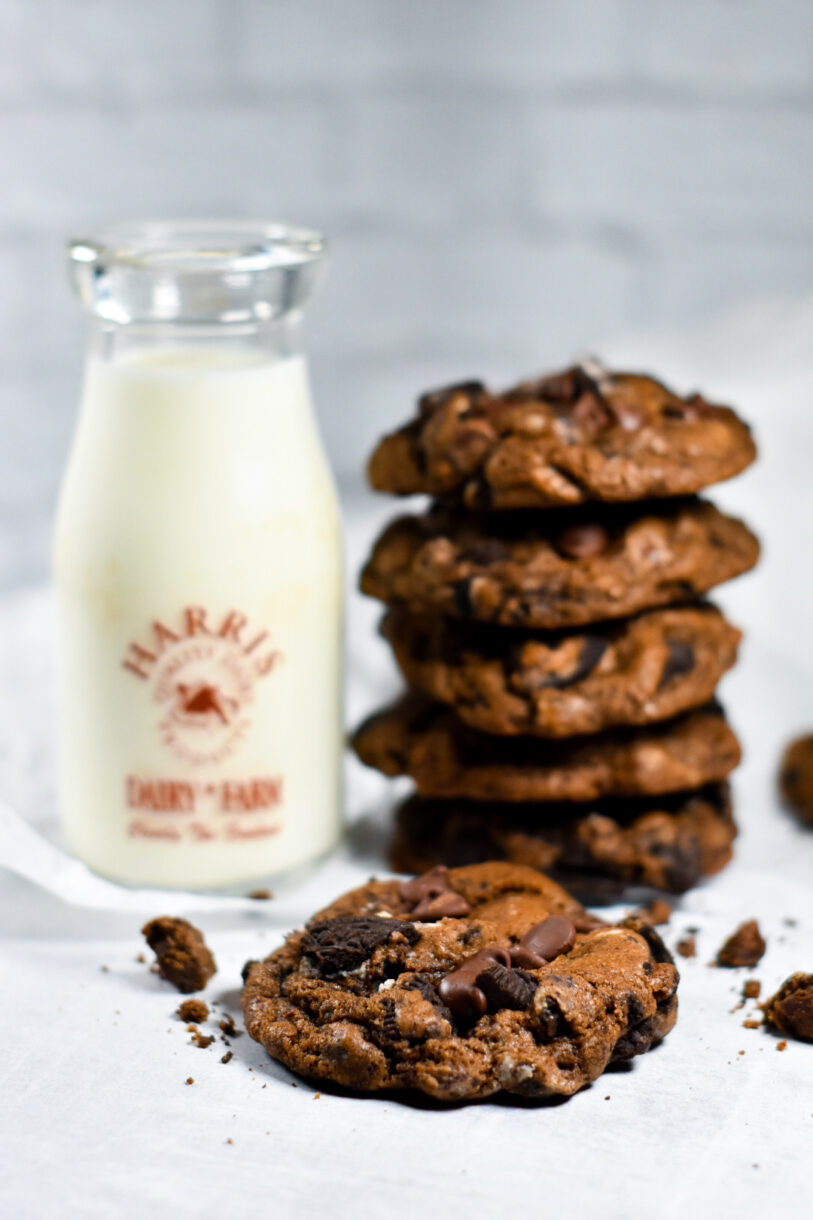 Bakery-Style Oreo cookies next to a jug of milk, on a white background