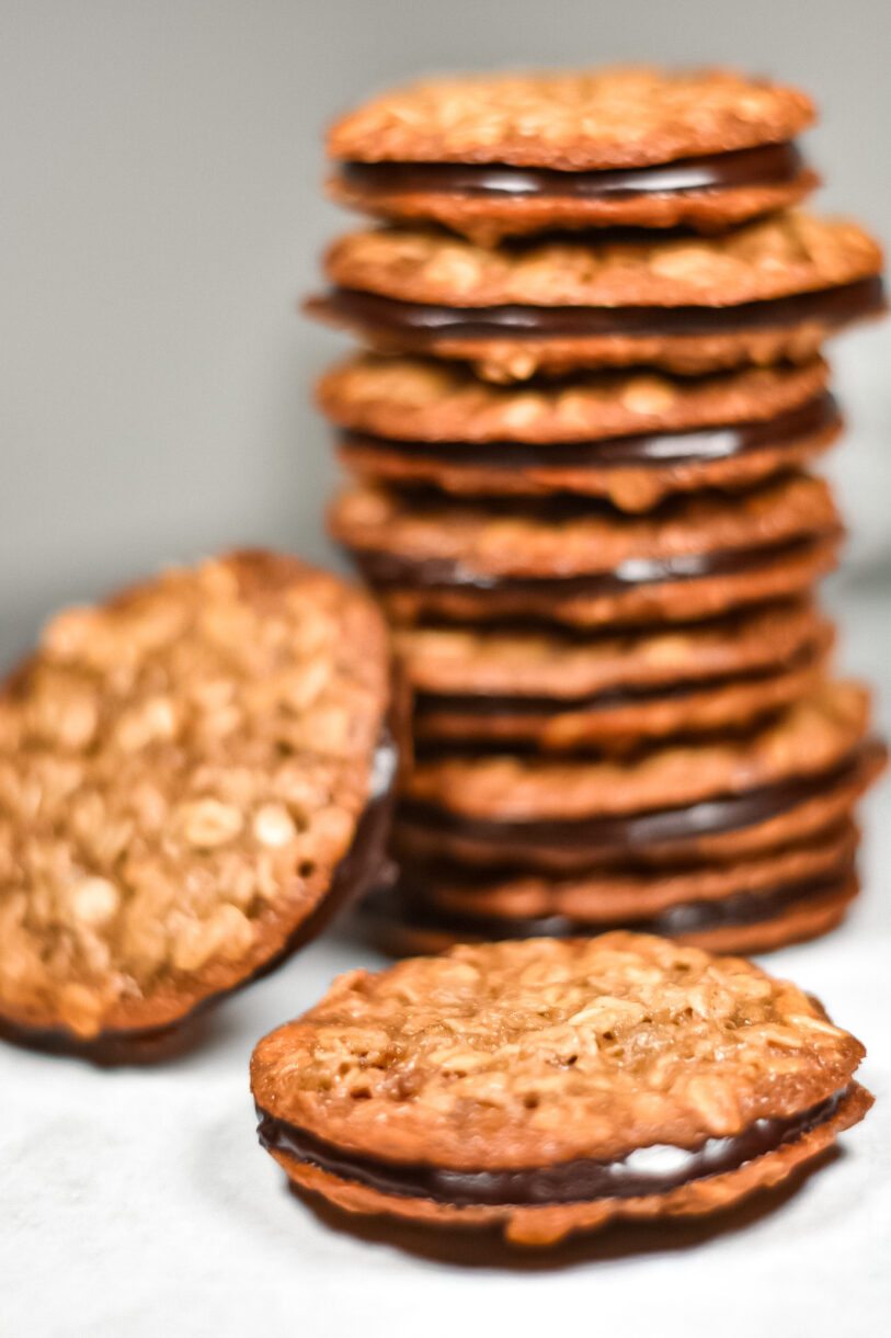 A single chai spiced oatmeal sandwich cookie in focus, with a tall stack of sandwich cookies behind