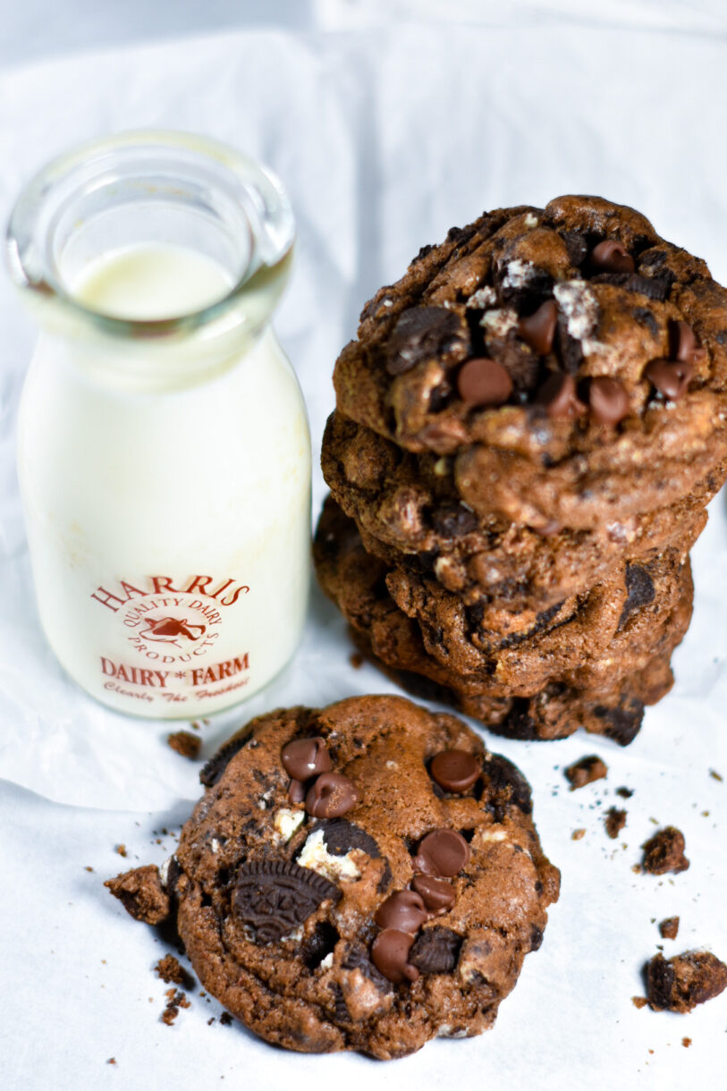 A stack of chocolate cookies and a milk jug on a white background