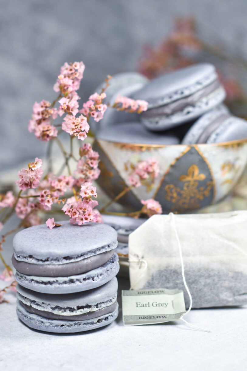 Purple macarons filled with Earl Grey ganache, in an antique teacup next to a tea bag