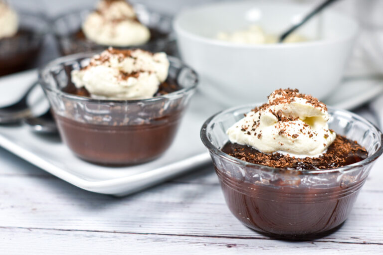 Glass bowls of chocolate Irish Cream pudding on a white tray, sitting on a white wood surface