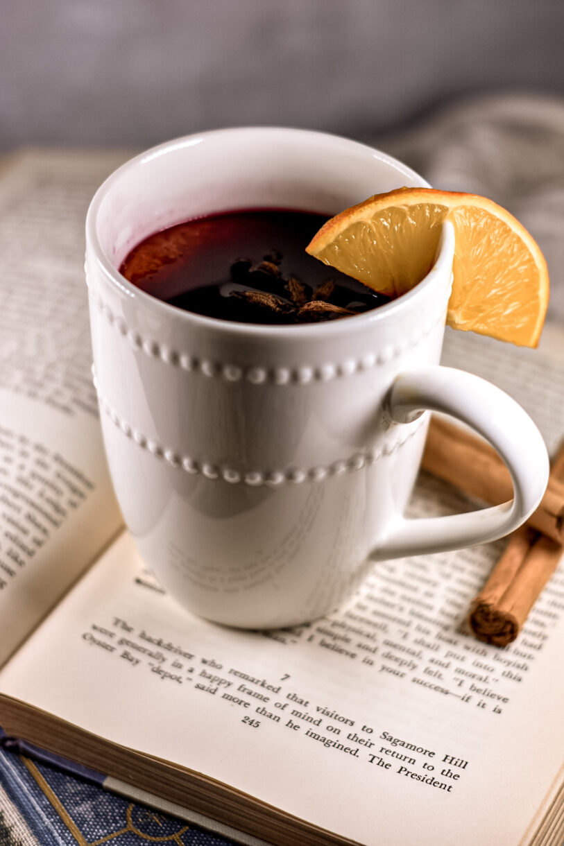 A white mug filled with mulled wine, sitting on top of a book