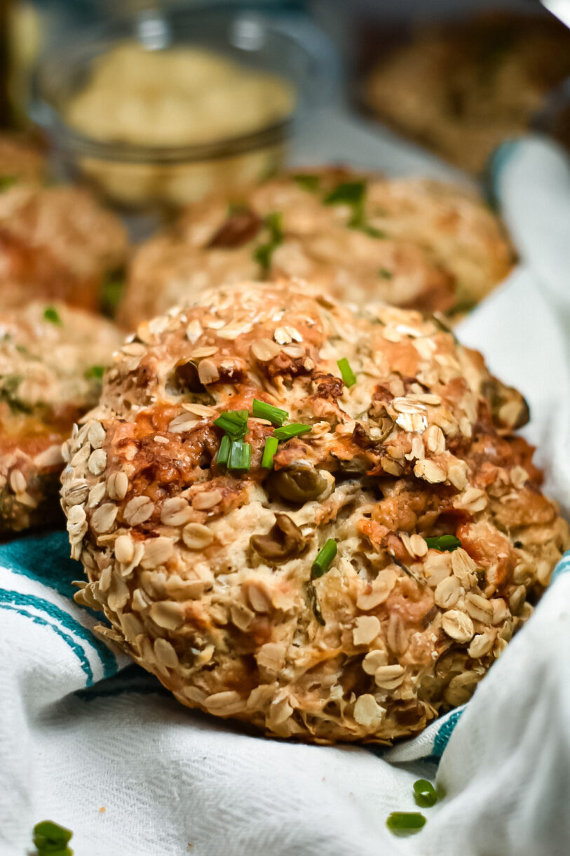 A loaf of oat covered bread garnished with fresh chives
