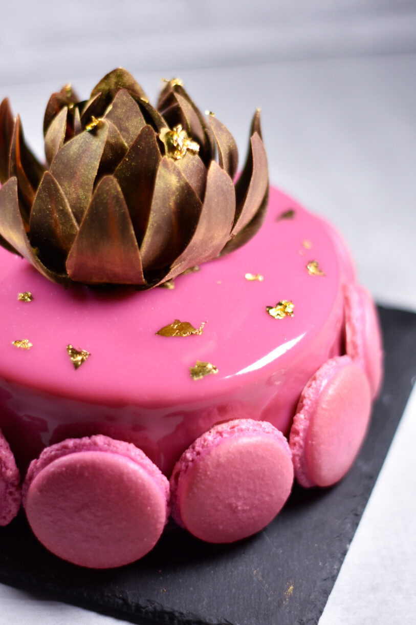 Closeup of gold tempered chocolate rose atop a passionfruit, coffee, and chocolate entremet